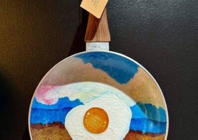 Over the Easy Planes VI, 2025, 12x8.5”, acrylics on decommissioned frying pan. Price: $250 Artist’s description: These whimsical pieces are a tribute to the hardworking cooks out there, recognizing their craft as fine art. It is also a tribute to all the used and abused frying pans in the world!
